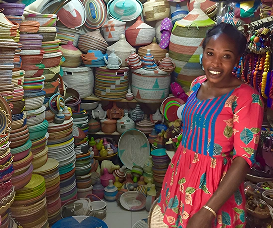boutique d’artisanat africain paniers colorés décorations femme souriante au marché Senegal'Art