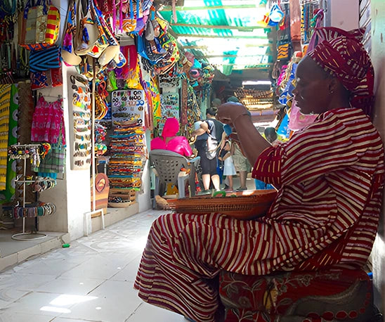 femme sénégalaise confectionnant des perles dans un marché coloré artisanat africain Senegal'Art